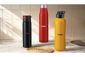 Three Prestige brand water bottles in black, red, and yellow colors, placed on a kitchen counter